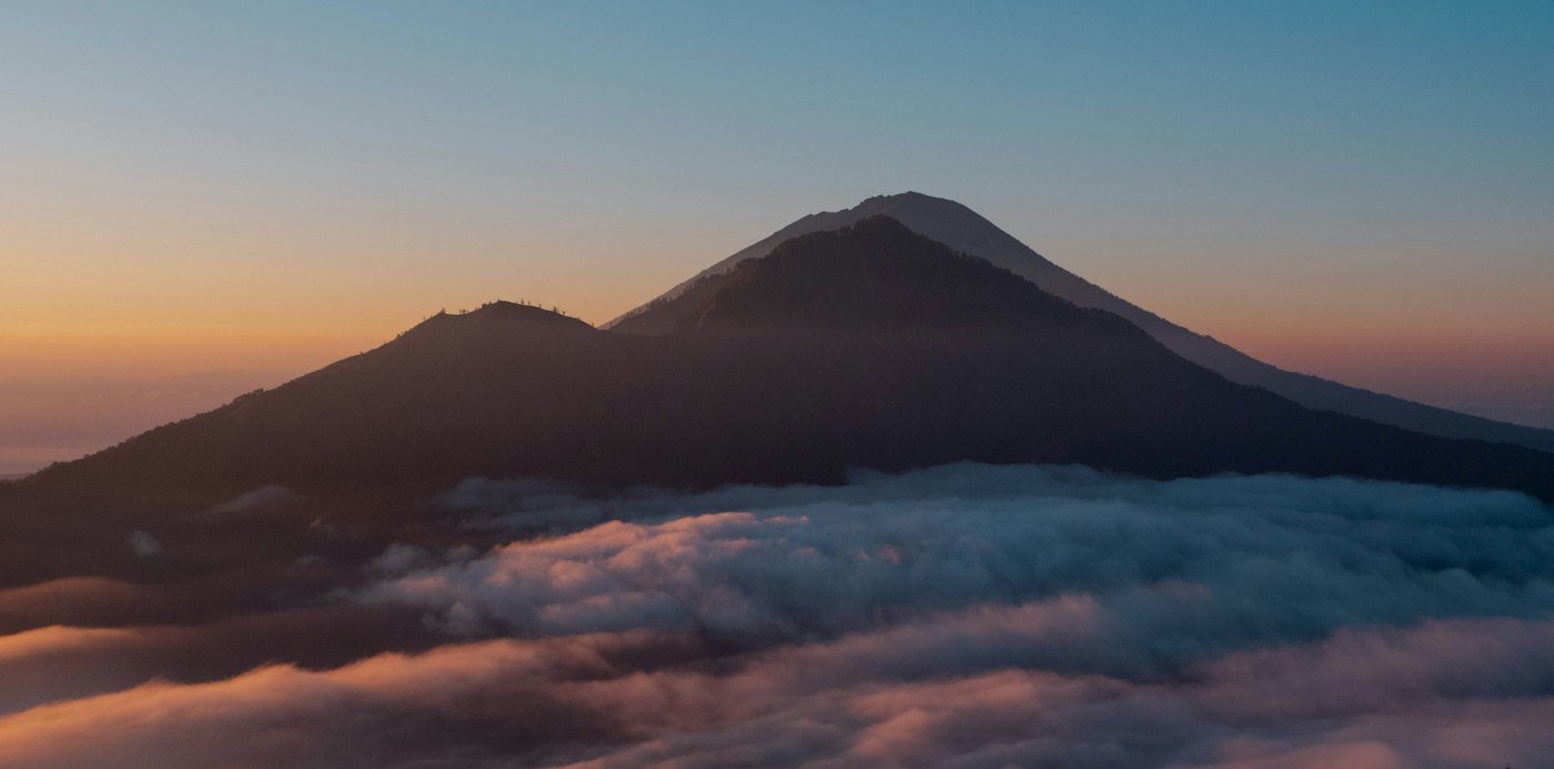 Mount Batur silhouette above the clouds at sunrise