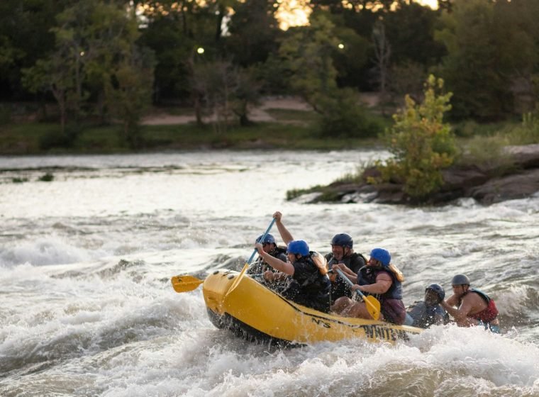 Raft splashing through white water surrounded by jungle