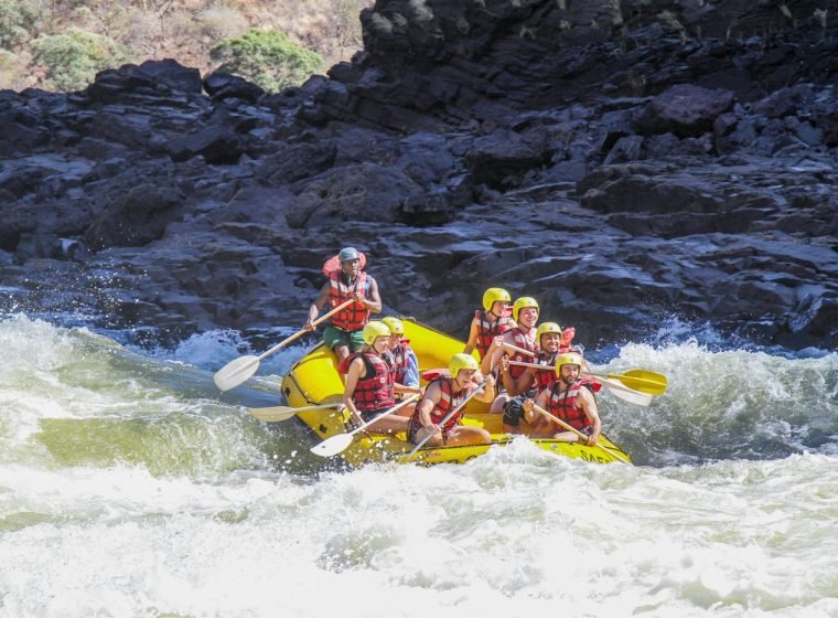 Smiling rafters paddling a yellow raft