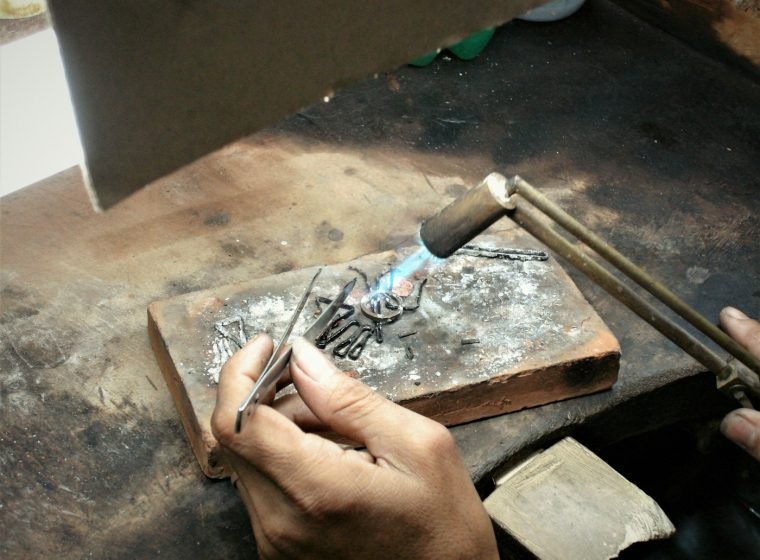 Craftsman engraving a silver plate with a hand tool