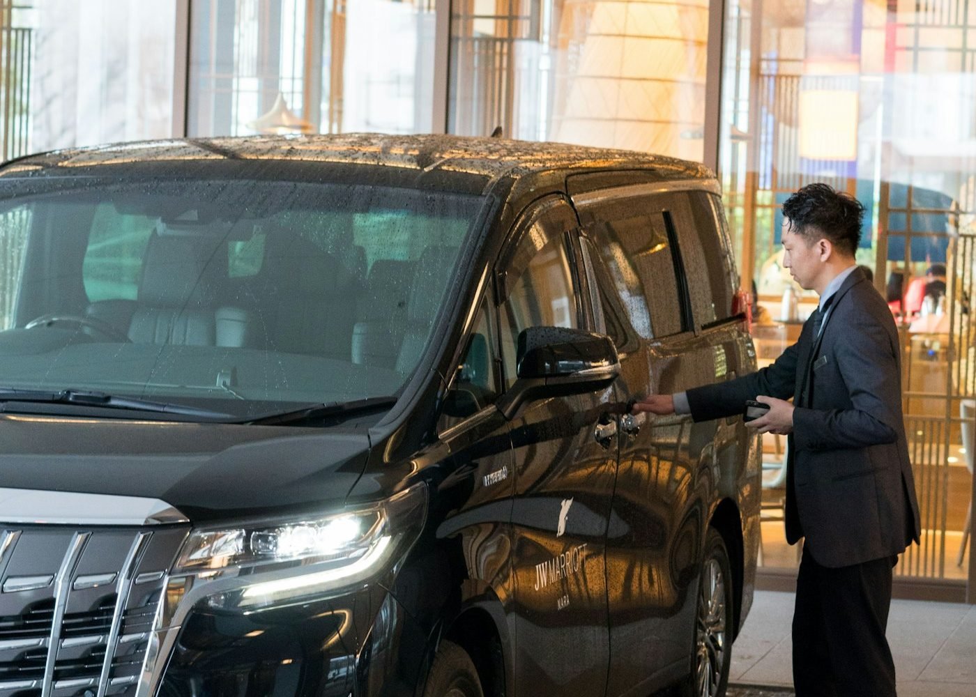 Chauffeur opening the door of a black Toyota Alphard